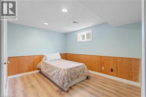 Room featuring light blue walls with wood paneling, wood-finish flooring, recessed lighting, and a white-framed window - 383 Bartley Bull Parkway, Brampton, ON - Indoor Photo Showing Bedroom