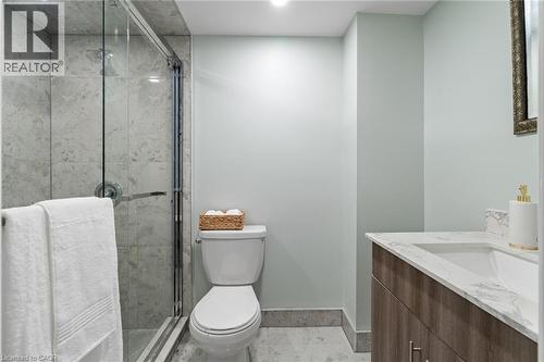 Bathroom featuring a glass-enclosed shower, light-toned wall tile, a white toilet, a wood-finish vanity with an integrated sink, and a stone-finish countertop - 383 Bartley Bull Parkway, Brampton, ON - Indoor Photo Showing Bathroom