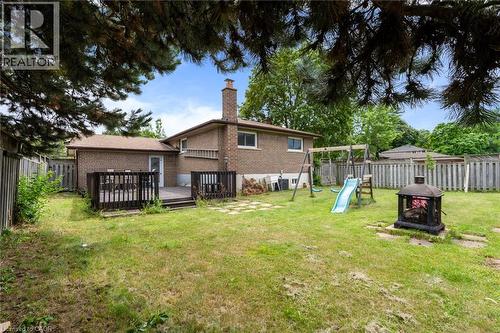 Expansive rear yard featuring a wood deck, perimeter fencing, brick exterior, and mature trees - 383 Bartley Bull Parkway, Brampton, ON - Outdoor With Backyard
