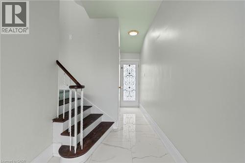 Foyer featuring a decorative glass panel entry door, white marble-look tile flooring, and a staircase with wood treads and a dark wood handrail - 383 Bartley Bull Parkway, Brampton, ON - Indoor Photo Showing Other Room