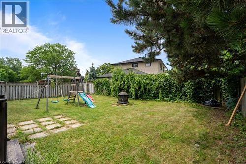 Spacious backyard featuring a manicured lawn, full privacy fencing, mature greenery, and a stone paver patio area - 383 Bartley Bull Parkway, Brampton, ON - Outdoor With Backyard