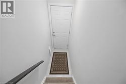Carpeted staircase with a dark wood handrail leading to a white paneled door - 