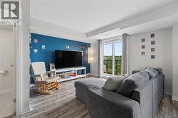 Living area with wood-finish flooring, a vibrant accent wall, and a sliding glass door leading to an outdoor balcony - 