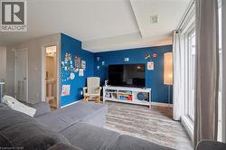 Open-concept room featuring wood-finish flooring, a wall-mounted television, and a large window with vertical blinds - 
