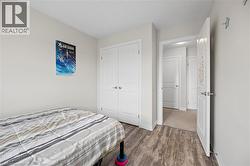Interior room featuring wood-finish flooring, light-colored walls, and a double-door closet with white panel doors and brushed nickel hardware - 