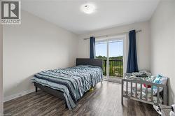 Room featuring wood-finish flooring, light neutral wall paint, and a sliding glass door providing outdoor access - 