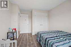 Room featuring wood-finish flooring, light neutral wall paint, white trim, and white bi-fold closet doors - 
