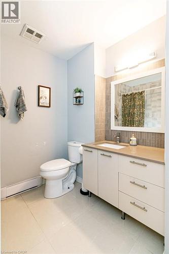 Bathroom featuring a white vanity with integrated sink, a light-toned countertop, and a tiled backsplash - 175 Hunter Street E Unit# 103, Hamilton, ON - Indoor Photo Showing Bathroom
