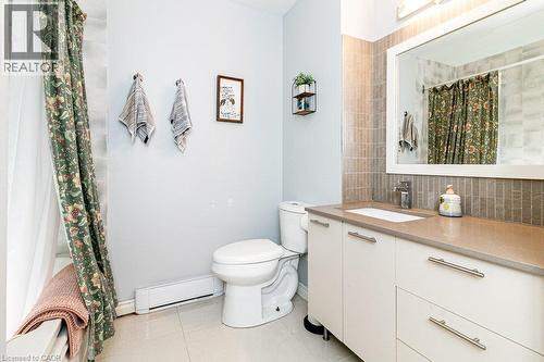 Contemporary bathroom featuring a white vanity with an integrated sink, a light-toned countertop, and modern cabinet hardware - 175 Hunter Street E Unit# 103, Hamilton, ON - Indoor Photo Showing Bathroom