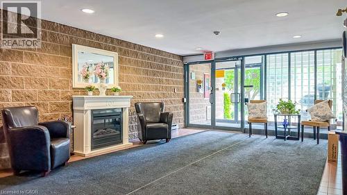 Lobby area featuring a decorative fireplace with a white mantel, recessed lighting, carpet flooring, and a stone-style accent wall - 175 Hunter Street E Unit# 103, Hamilton, ON - Indoor With Fireplace