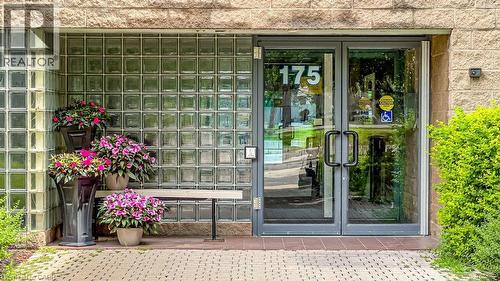Glass block wall and stone facade exterior featuring a double-door entry with dark framing and hardware - 175 Hunter Street E Unit# 103, Hamilton, ON - Outdoor