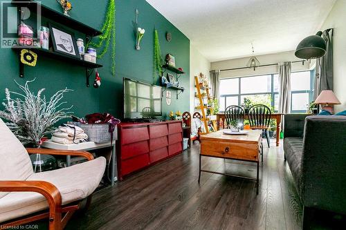 Spacious living area featuring dark wood-finish flooring, a vibrant accent wall, built-in shelving, large windows with natural light, and recessed ceiling lighting - 175 Hunter Street E Unit# 103, Hamilton, ON - Indoor