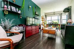 Spacious living area featuring dark wood-finish flooring, a vibrant accent wall, built-in shelving, large windows with natural light, and recessed ceiling lighting - 