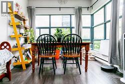 Dining area featuring dark wood-finish flooring, a wood dining table, and extensive window walls with dark frames - 