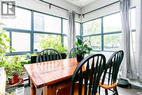 Room featuring extensive window walls with dark framing, providing abundant natural light - 175 Hunter Street E Unit# 103, Hamilton, ON - Indoor Photo Showing Dining Room