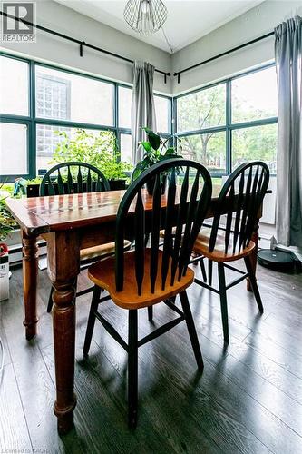 Room featuring corner window banks, wood-finish flooring, and a contemporary pendant light fixture - 175 Hunter Street E Unit# 103, Hamilton, ON - Indoor