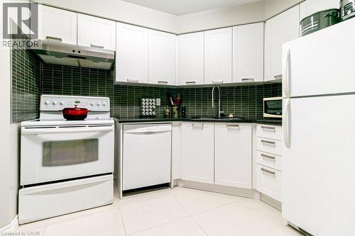 Kitchen featuring white cabinetry, dark tile backsplash, black countertops, and integrated appliances - 175 Hunter Street E Unit# 103, Hamilton, ON - Indoor Photo Showing Kitchen