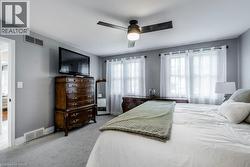 Carpeted room with light gray walls, two double-hung windows, and an overhead ceiling fan with integrated lighting - 