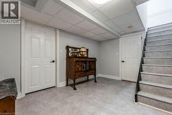 Finished lower level featuring light gray walls, a drop ceiling, and gray tile flooring - 
