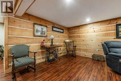 Room featuring wood-finish flooring, natural wood paneled walls, and a recessed ceiling light fixture - 