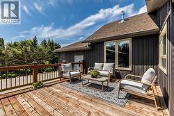 Expansive wood deck with dark wood railing and black spindles, offering privacy with surrounding mature trees - 