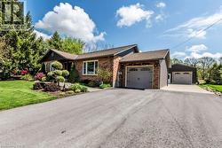 Brick exterior with grey siding accents, featuring a two-car attached garage and a separate two-car detached garage - 