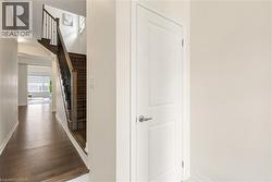 Entryway featuring dark wood-finish flooring, a contemporary staircase with iron balusters, a solid panel interior door, and light-colored wall finishes - 