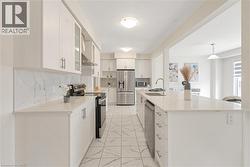 Contemporary kitchen featuring white cabinetry, stainless steel appliances, and light-toned countertops with a matching backsplash - 