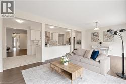 Open-concept living area featuring dark wood-finish flooring, light wall colors, and a central overhead pendant light - 