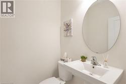 Contemporary bathroom featuring a wall-mounted sink with chrome faucet, circular frameless mirror, and a white toilet - 