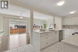 Contemporary kitchen featuring white cabinetry, light countertops, and tile flooring - 
