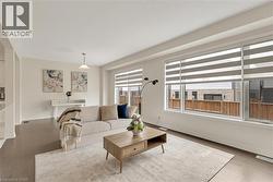 Living area featuring wood-finish flooring, light neutral wall tones, and multiple large windows with horizontal blinds - 
