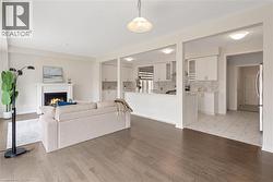 Open concept living area with dark wood-finish flooring, a classic white fireplace with mantel, and recessed lighting - 