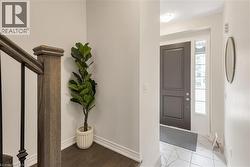 Foyer featuring a dark paneled entry door with sidelight, marble-look tile flooring, and a modern circular mirror - 