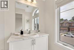 Bathroom vanity featuring a white cabinet with brushed nickel hardware, an integrated sink, and a stone-finish countertop - 