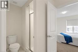Bathroom featuring a white toilet, tiled flooring, and a glass-enclosed shower - 