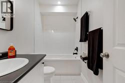 Bathroom featuring a white vanity with a dark countertop, an undermount sink, and black fixtures - 