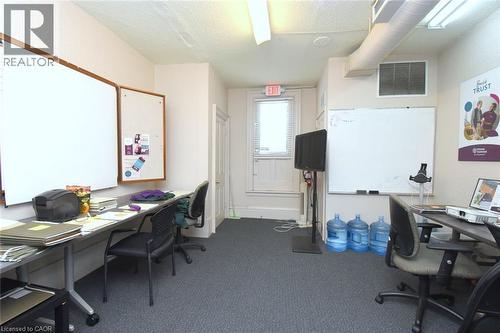 Carpeted interior space featuring multiple wall-mounted whiteboards, built-in shelving, and exposed ceiling ductwork - 108 George Street, Hamilton, ON 