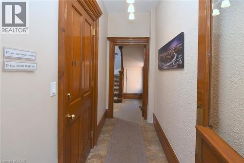Hallway featuring wood-finish doors and trim, textured wall finishes, and a combination of tile and carpet flooring - 108 George Street, Hamilton, ON 