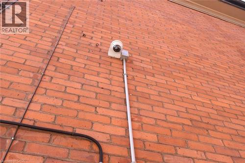 Red brick exterior with a visible security camera system and conduit - 108 George Street, Hamilton, ON 