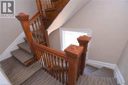 Staircase featuring wood balusters, carved newel posts, and patterned carpet runners - 108 George Street, Hamilton, ON 