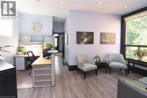 Open-concept interior featuring wood-finish flooring, recessed lighting, and a large window with exterior foliage - 108 George Street, Hamilton, ON 