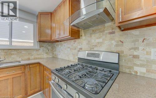 Kitchen featuring warm wood cabinetry, a stainless steel gas range, and a coordinating range hood with a glass canopy - 80 Lower Canada Crescent, Kitchener, ON - Indoor Photo Showing Kitchen