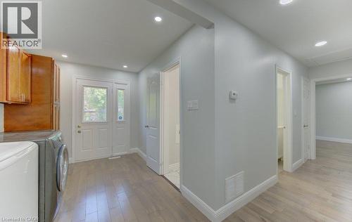 Spacious utility area featuring wood-finish flooring, recessed lighting, and a white paneled door with sidelight - 80 Lower Canada Crescent, Kitchener, ON - Indoor Photo Showing Laundry Room