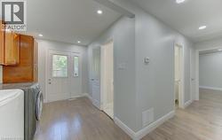 Spacious utility area featuring wood-finish flooring, recessed lighting, and a white paneled door with sidelight - 