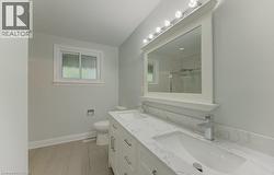 Bathroom featuring a double vanity with stone-finish countertops, undermount sinks, and chrome faucets - 