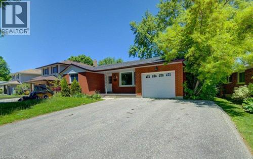 Brick exterior featuring a single-car garage with an arched window door, a paved driveway, and mature landscaping - 80 Lower Canada Crescent, Kitchener, ON - Outdoor