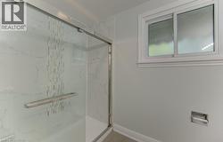 Glass-enclosed shower featuring white marble-look paneling and a decorative tile accent - 