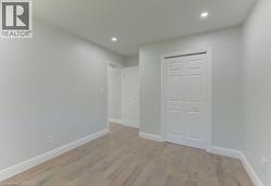 Interior room featuring light wood-finish flooring, white baseboards, and light gray wall paint - 