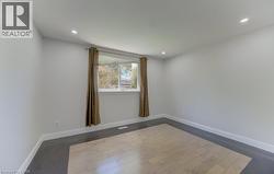 Room featuring light wood-finish flooring with a dark perimeter border, recessed lighting, and a window with white trim - 